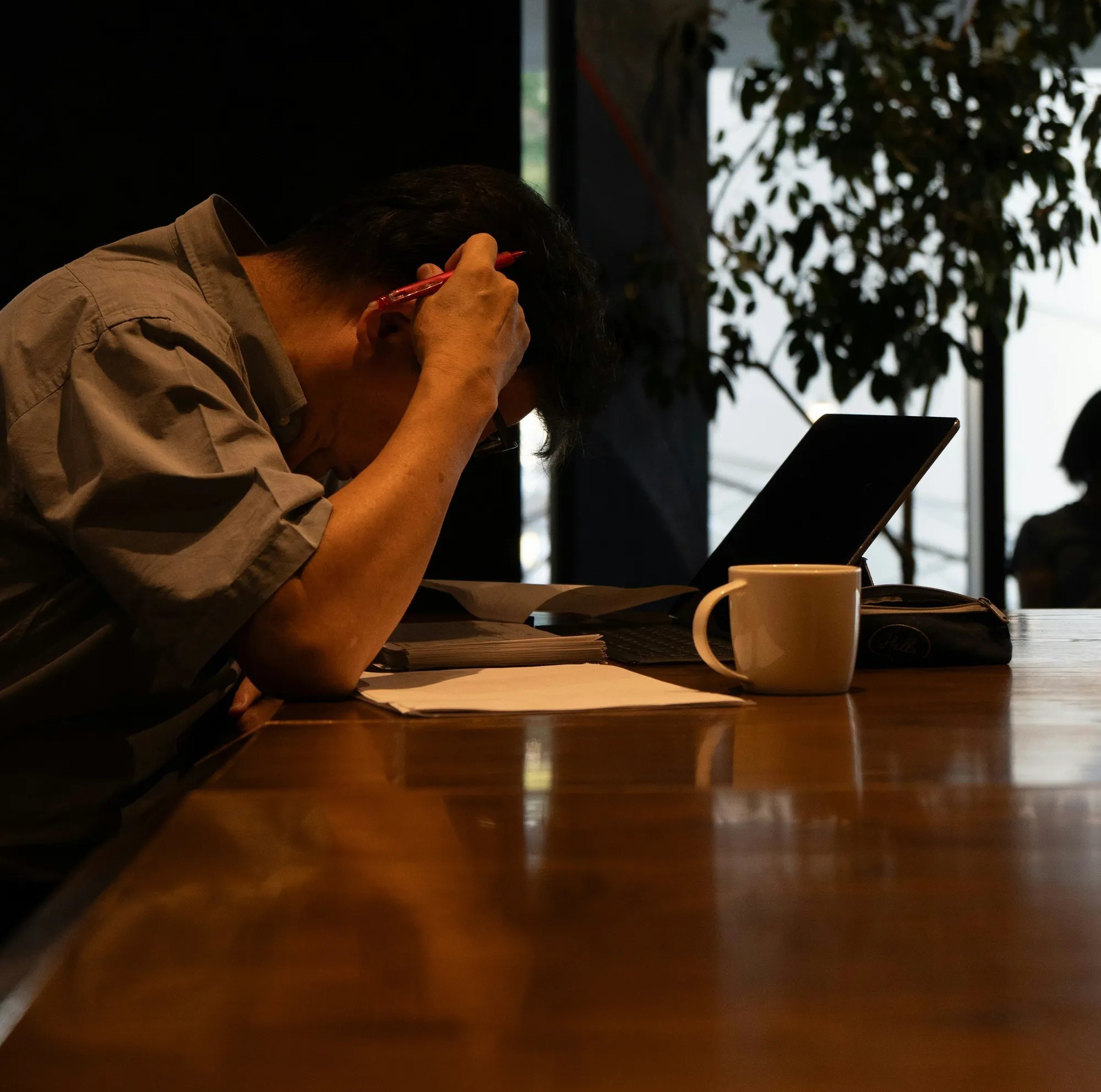 Frustrated man at desk with laptop and documents showing claim stress or paperwork overload