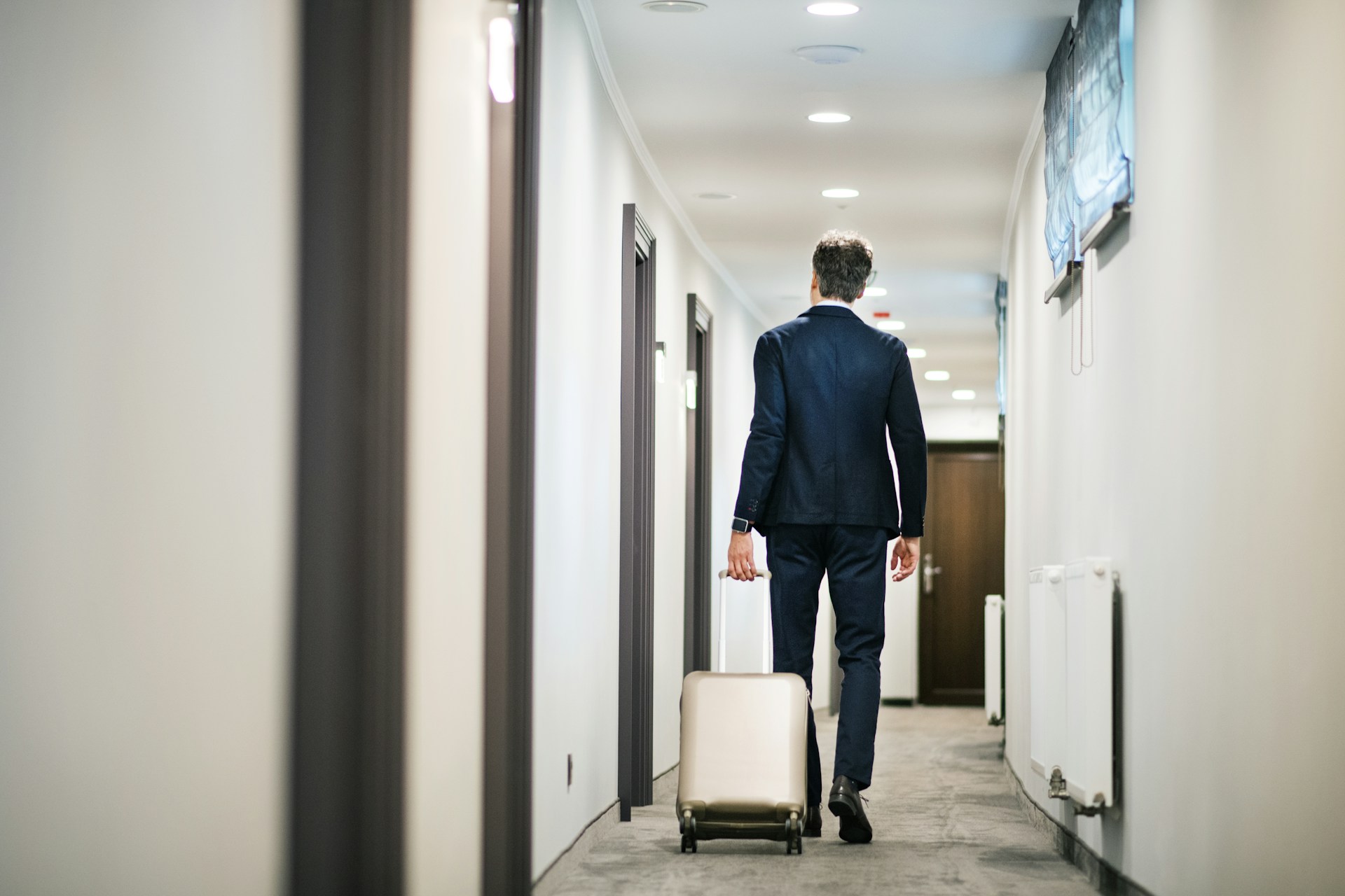 Business traveler walking through hotel hallway, symbolizing commercial property use