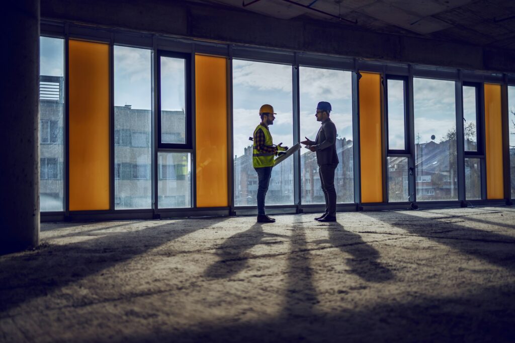 Construction manager and property owner discussing project plans inside a partially completed commercial building.