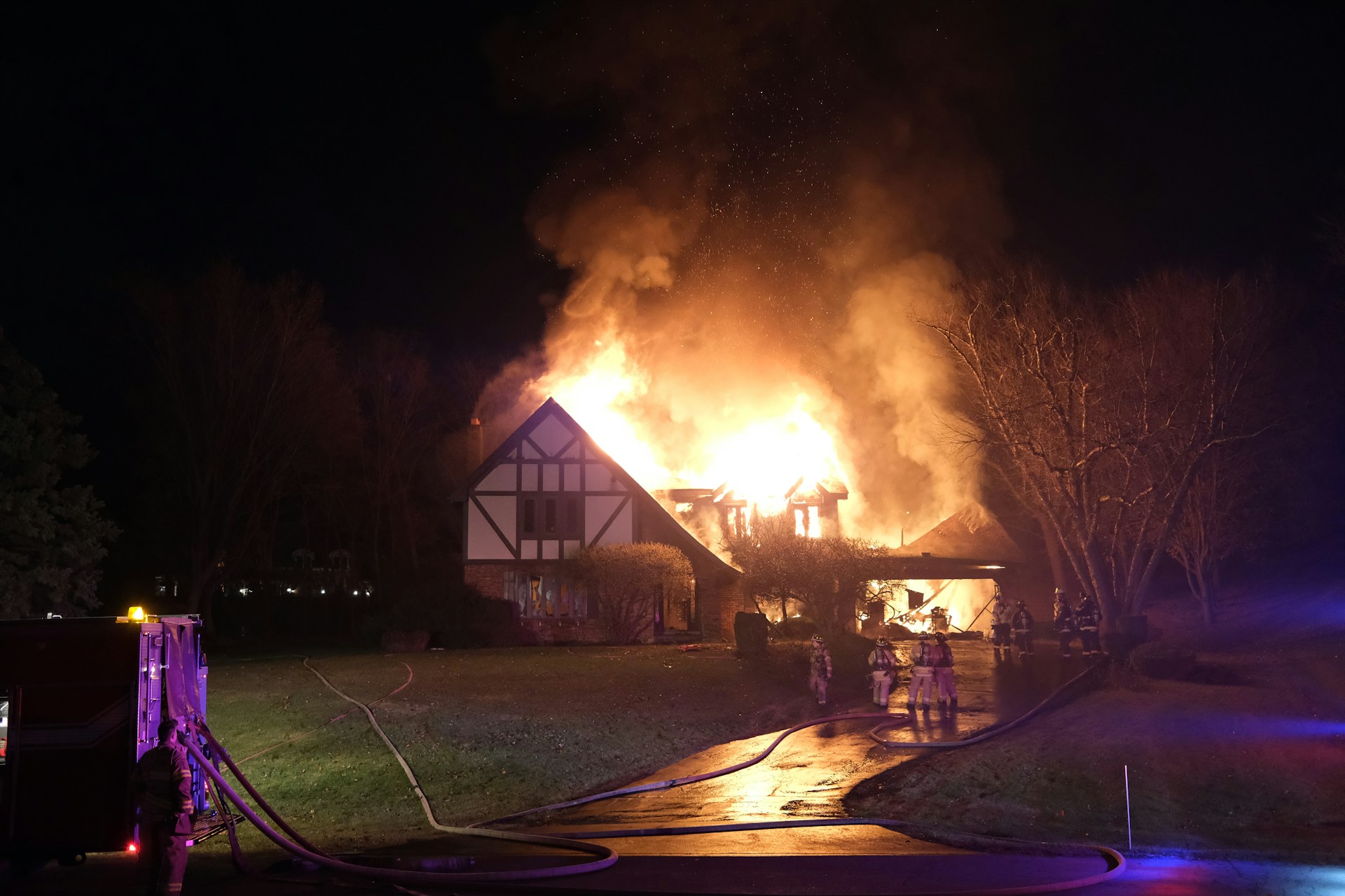 Firefighters battling a house fire at night showing total residential property loss