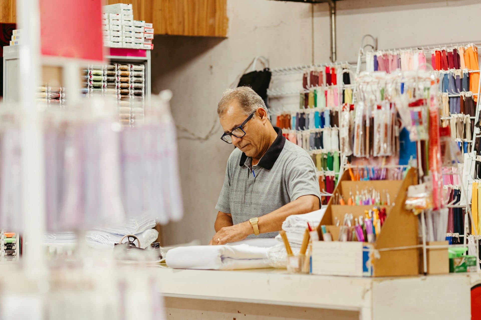 Small business owner working in a fabric supply shop surrounded by colorful inventory
