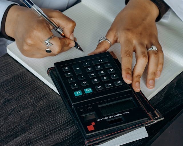 Close up of hands using calculator and writing notes during insurance claim review