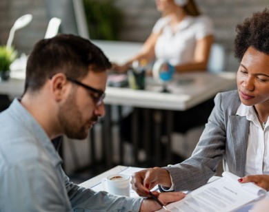 Public adjuster explaining insurance paperwork to a client during office meeting