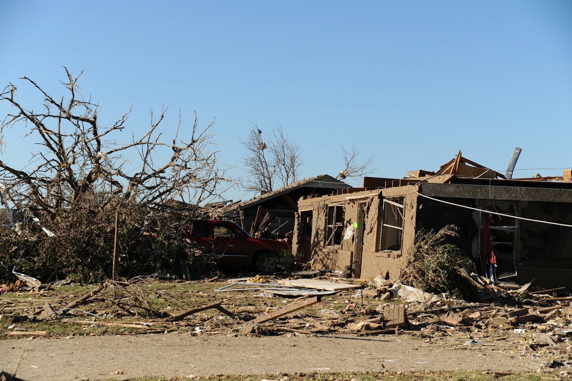 Severe tornado damage to residential homes with debris and fallen trees