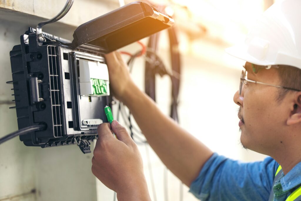 Professional technician connecting wires inside a home automation control box