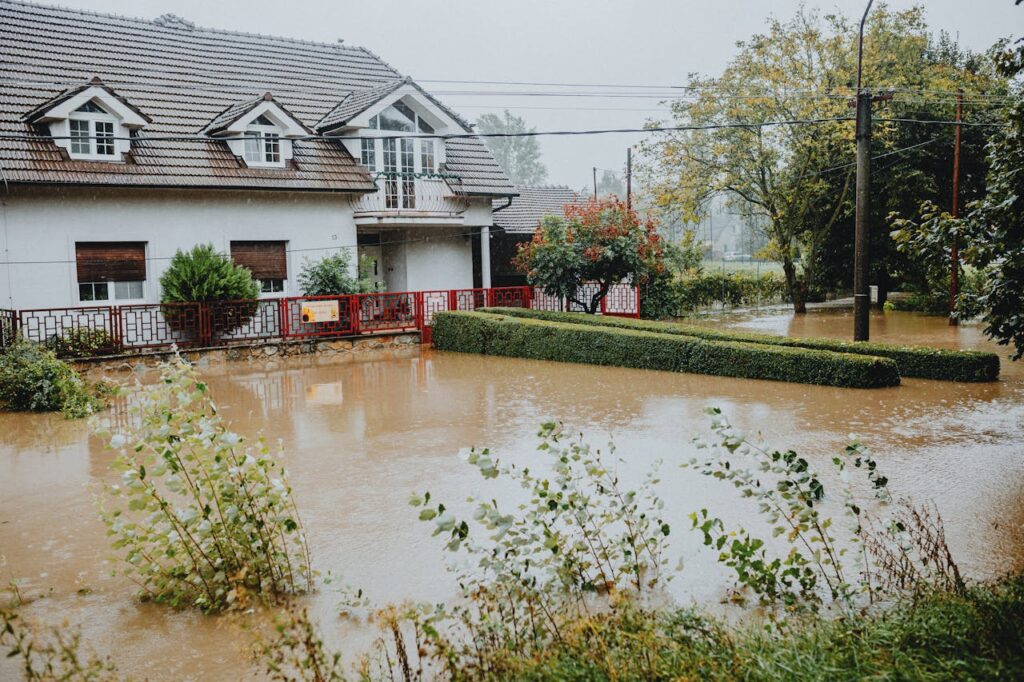 Residential home with significant flood damage in front yard after heavy rainfall