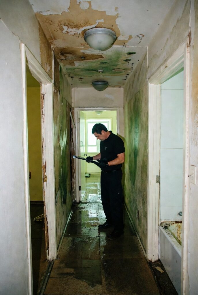 Public adjuster inspecting condo water damage with a moisture meter