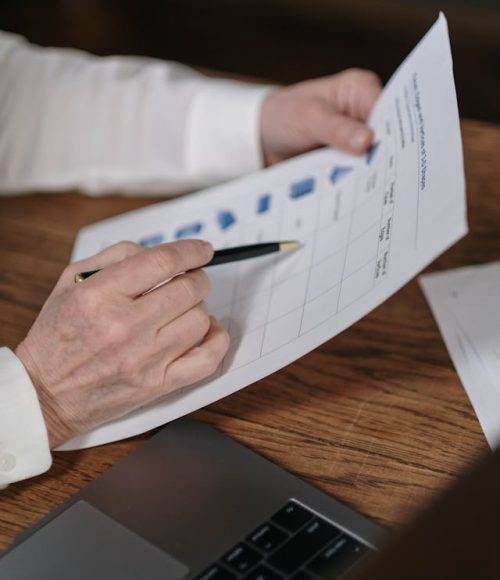 Professional reviewing printed insurance document with charts and checklist at a desk